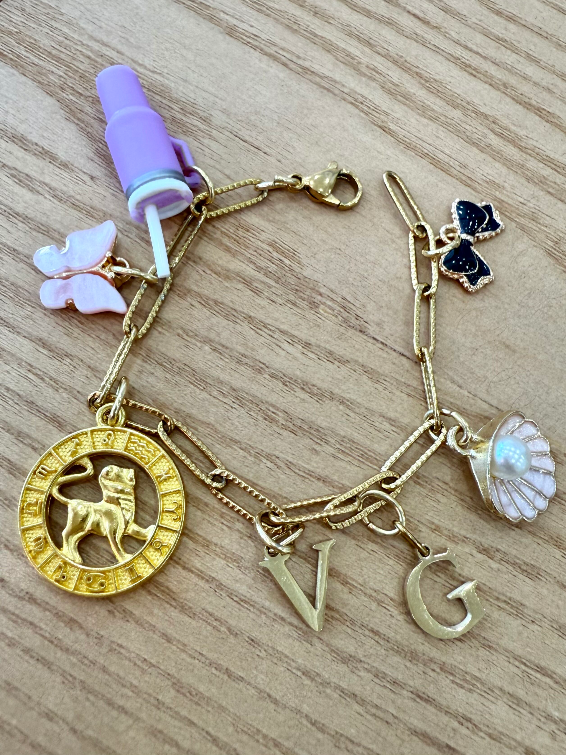 Gold custom charm bracelet featuring various miniature pendants and initial charms